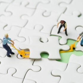 Teamwork, fulfill the missing piece for business success strategy concept, miniature workers team help using the forklift to complete the missing white jigsaw puzzle piece on pastel green background.