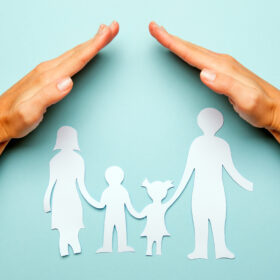 Paper family in hand isolated on blue background