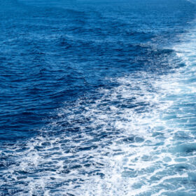 Boat white wake, on blue sea background, view from the ship. Mediterranean sea cruise, greek islands summer vacation concept